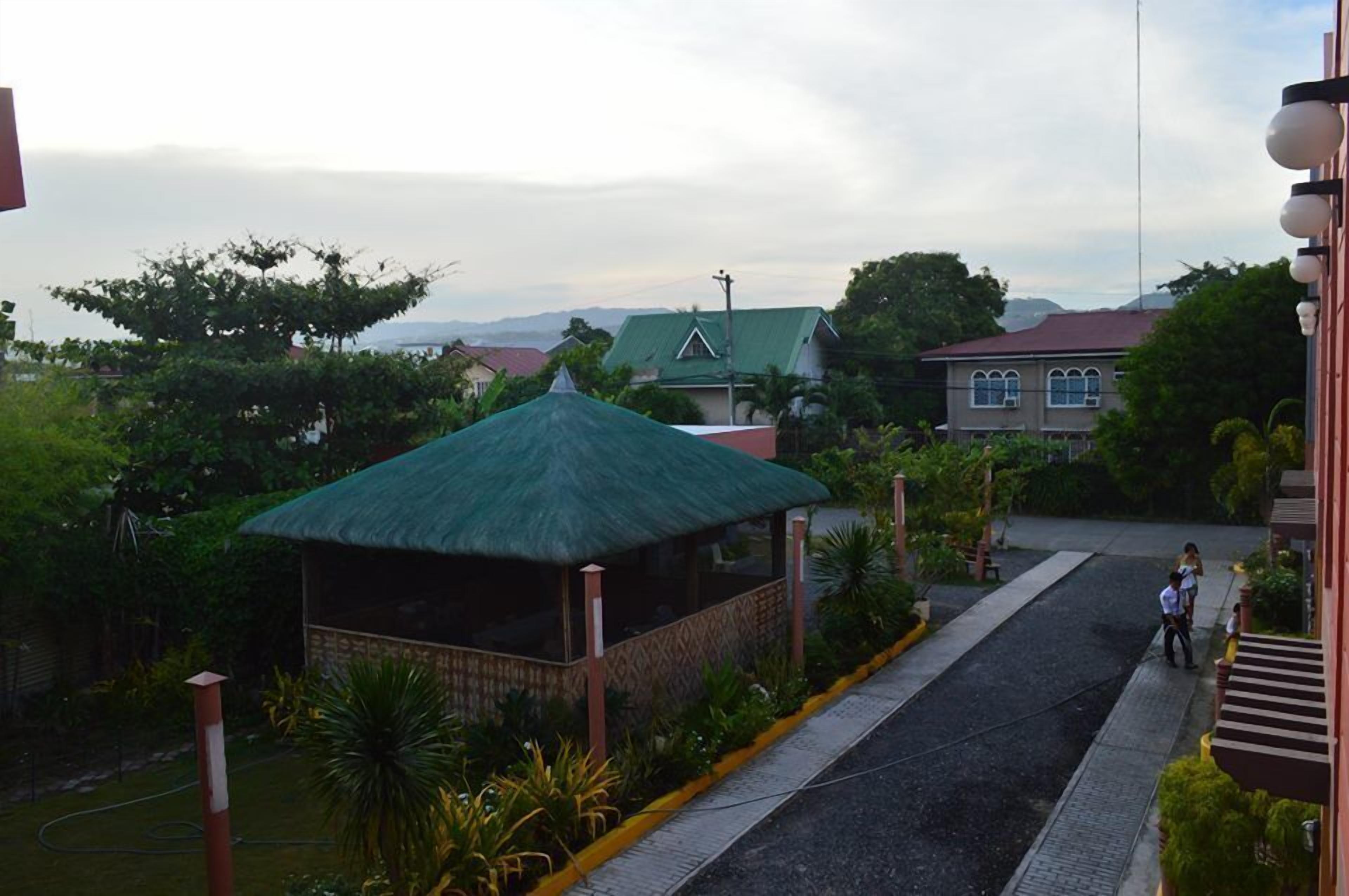 A building with a green-roofed structure, a paved road, and surrounding greenery.