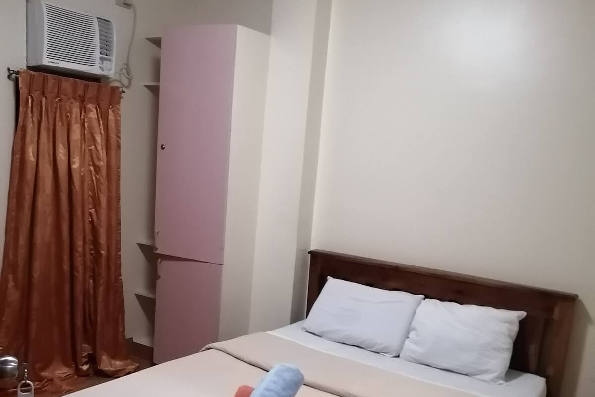 Quarto com cama, guarda-roupa e ar condicionado.