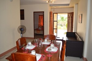 Comedor con una mesa dispuesta para cuatro, un ventilador y vistas al exterior.