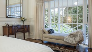 A bedroom with a large window, a sofa, a wooden dresser, and a mirror. - Moulton Park Homestead (Sassafras)