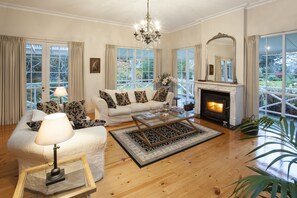 A living room with a fireplace, a sofa set, a coffee table, and a chandelier.