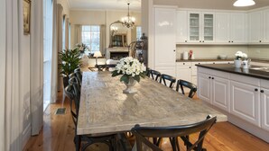 A spacious dining room with a large wooden table, surrounded by chairs, and a chandelier. - Moulton Park Homestead (Sassafras)