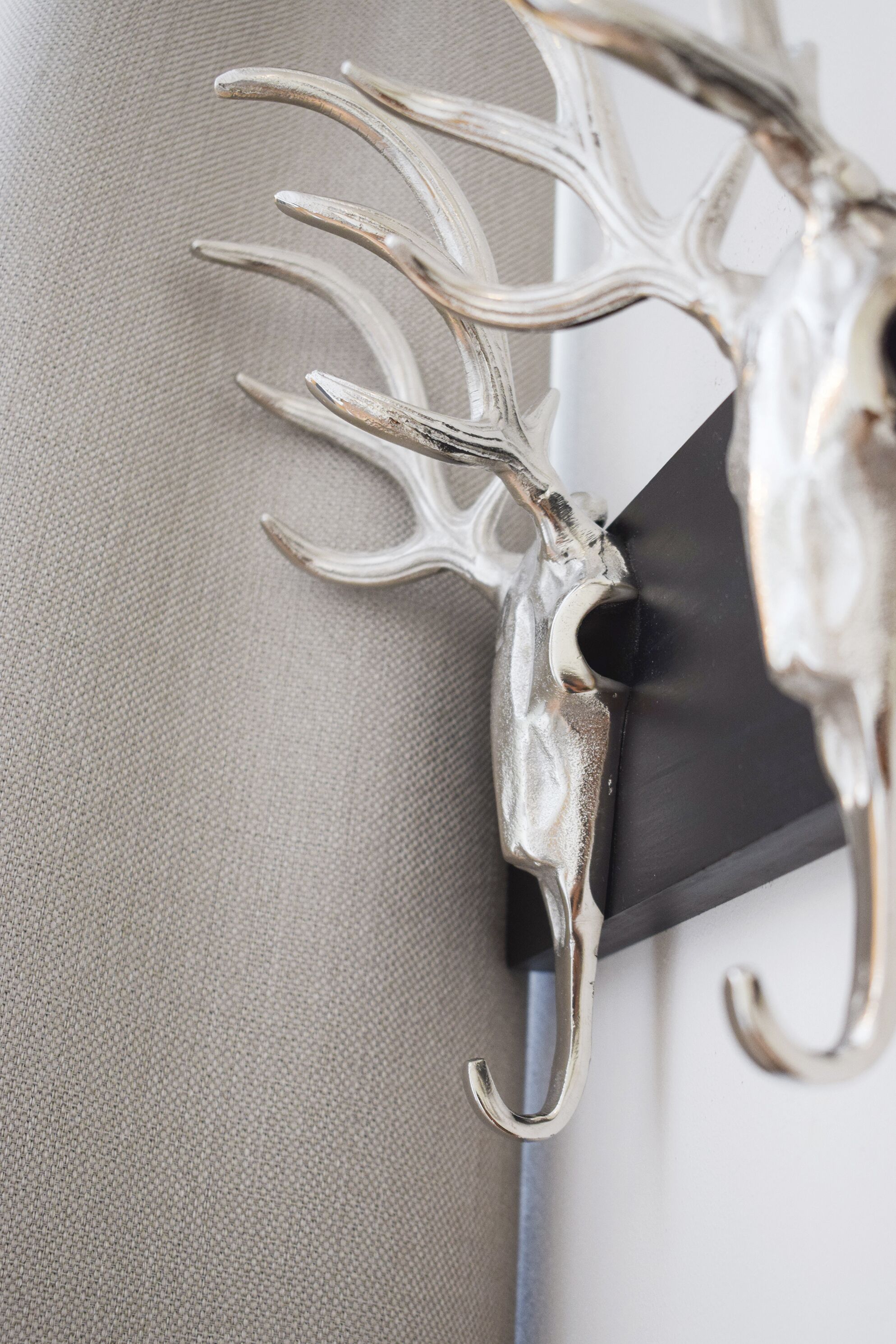 A metallic deer head sculpture mounted on a textured wall.