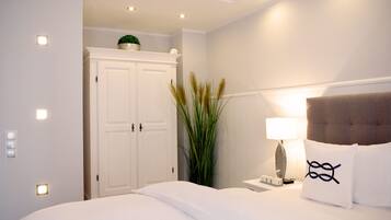 Ein Hotelzimmer mit Bett, Nachttisch, Lampe, Pflanze und Kleiderschrank.