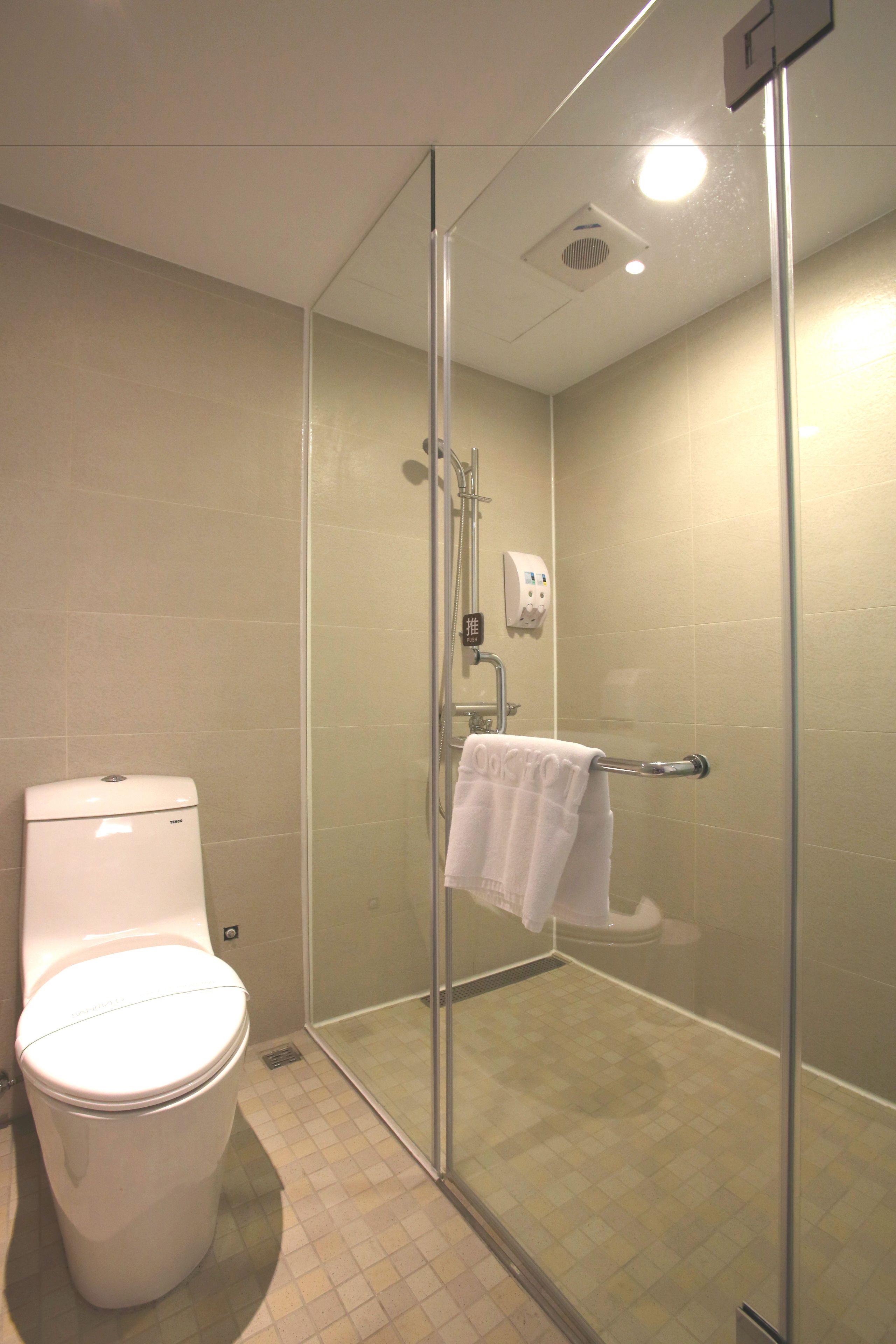 A modern bathroom with a toilet, a glass shower enclosure, and a towel rack.