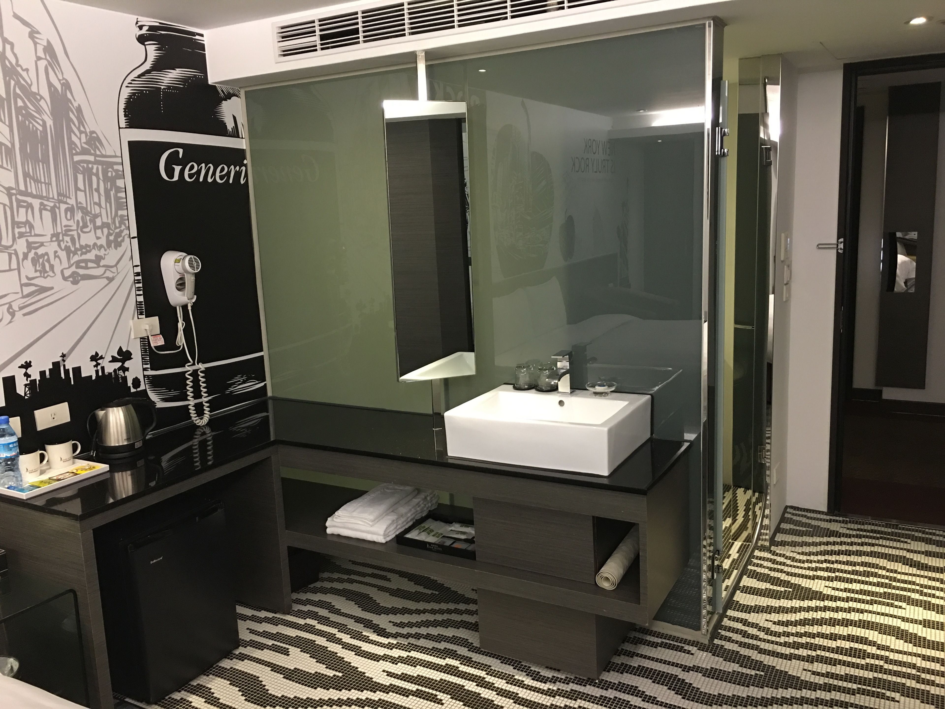 Une salle de bain moderne avec un grand miroir, un lavabo blanc et un meuble-lavabo noir.