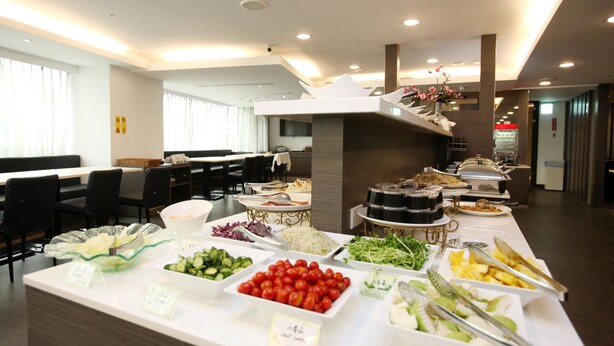 Un bufé con diversos alimentos y una zona de estar con mesas y sillas.