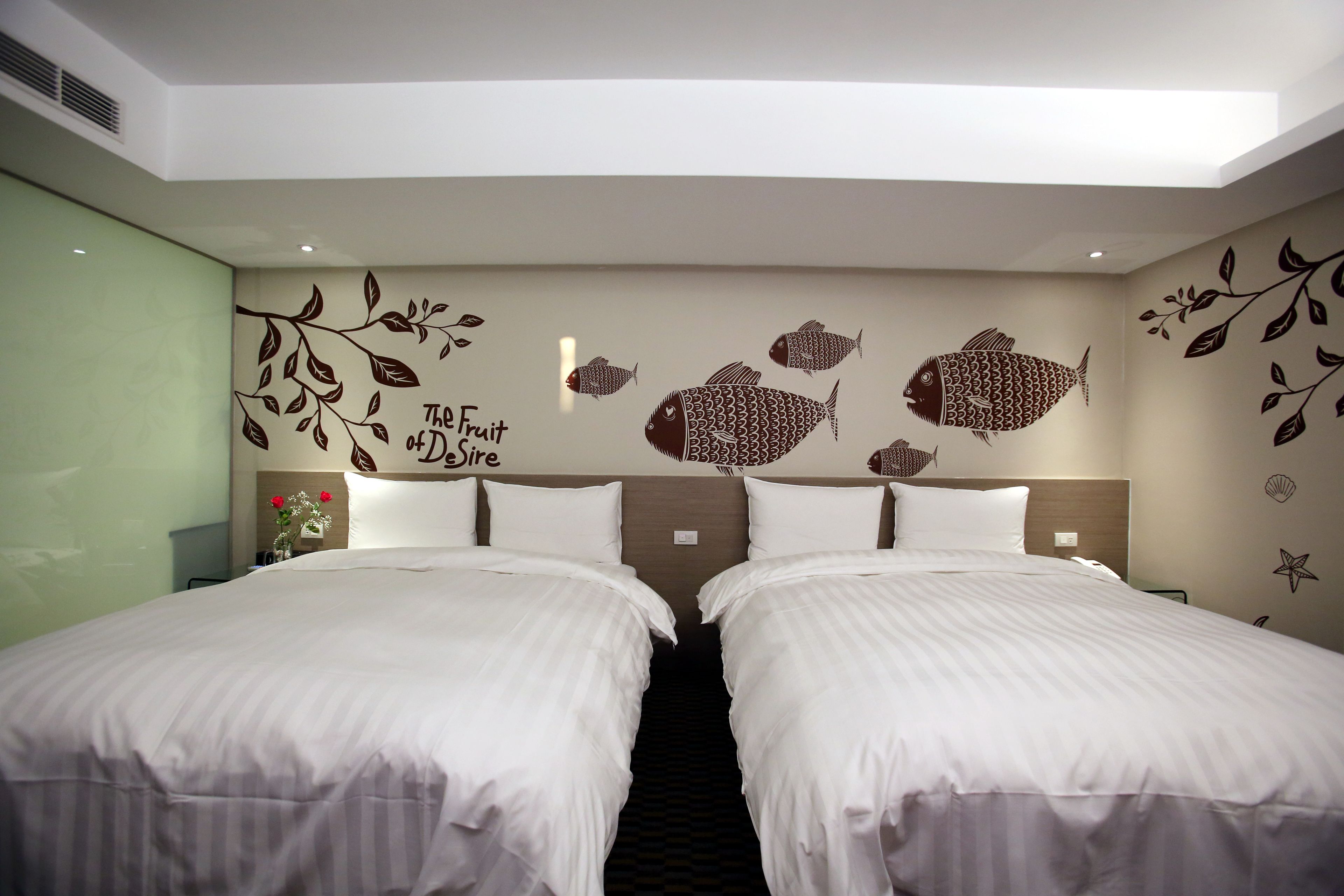 A hotel room with two beds, a wall with fish and leaf decals, and a sign that says "The Fruit & Dairies".