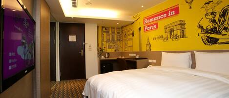 Habitación de hotel con cama, escritorio y una pared decorada con motivos de París.