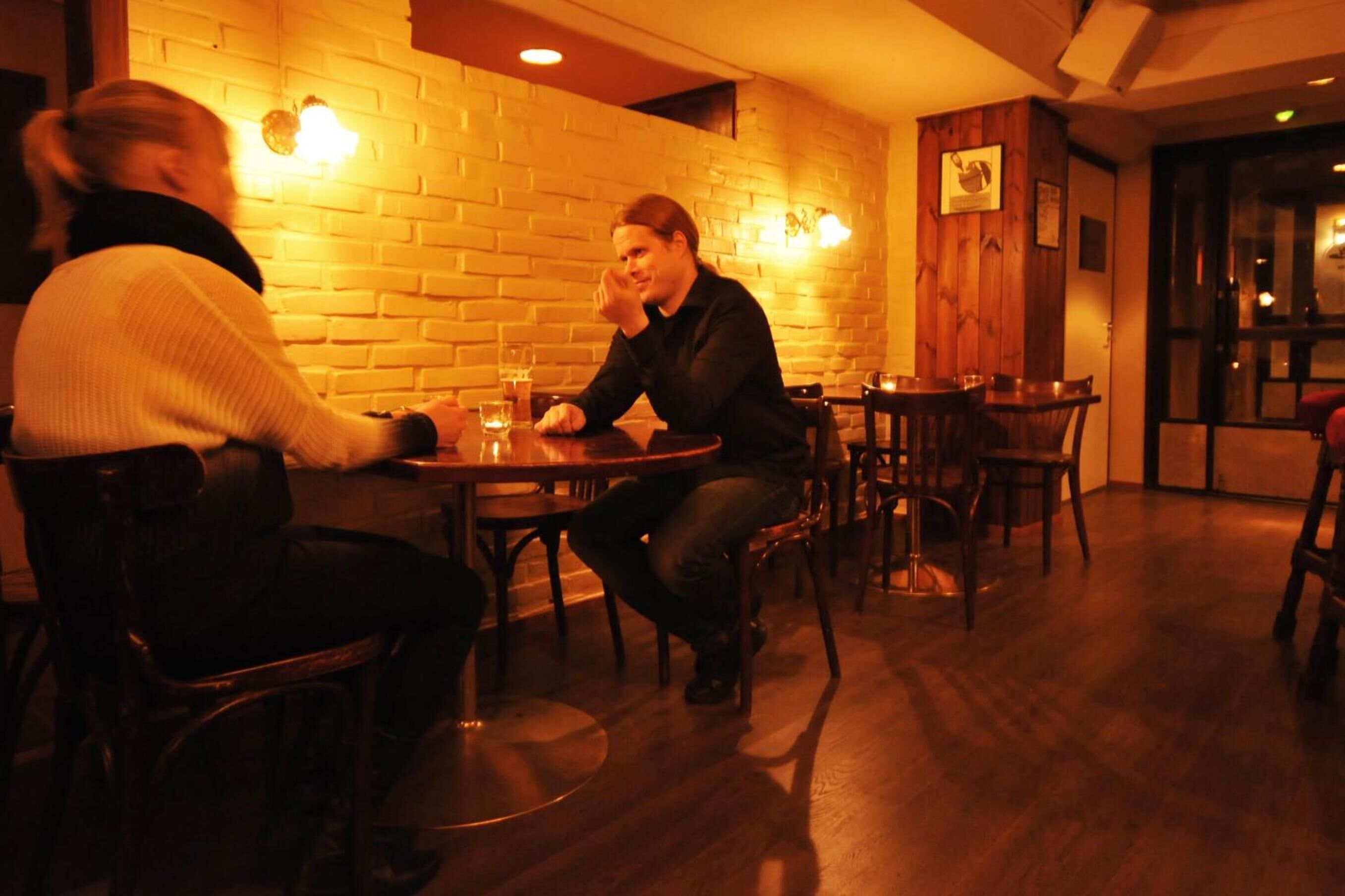 Ravintola, jossa on tiiliseinät, puiset pöydät ja tuolit.