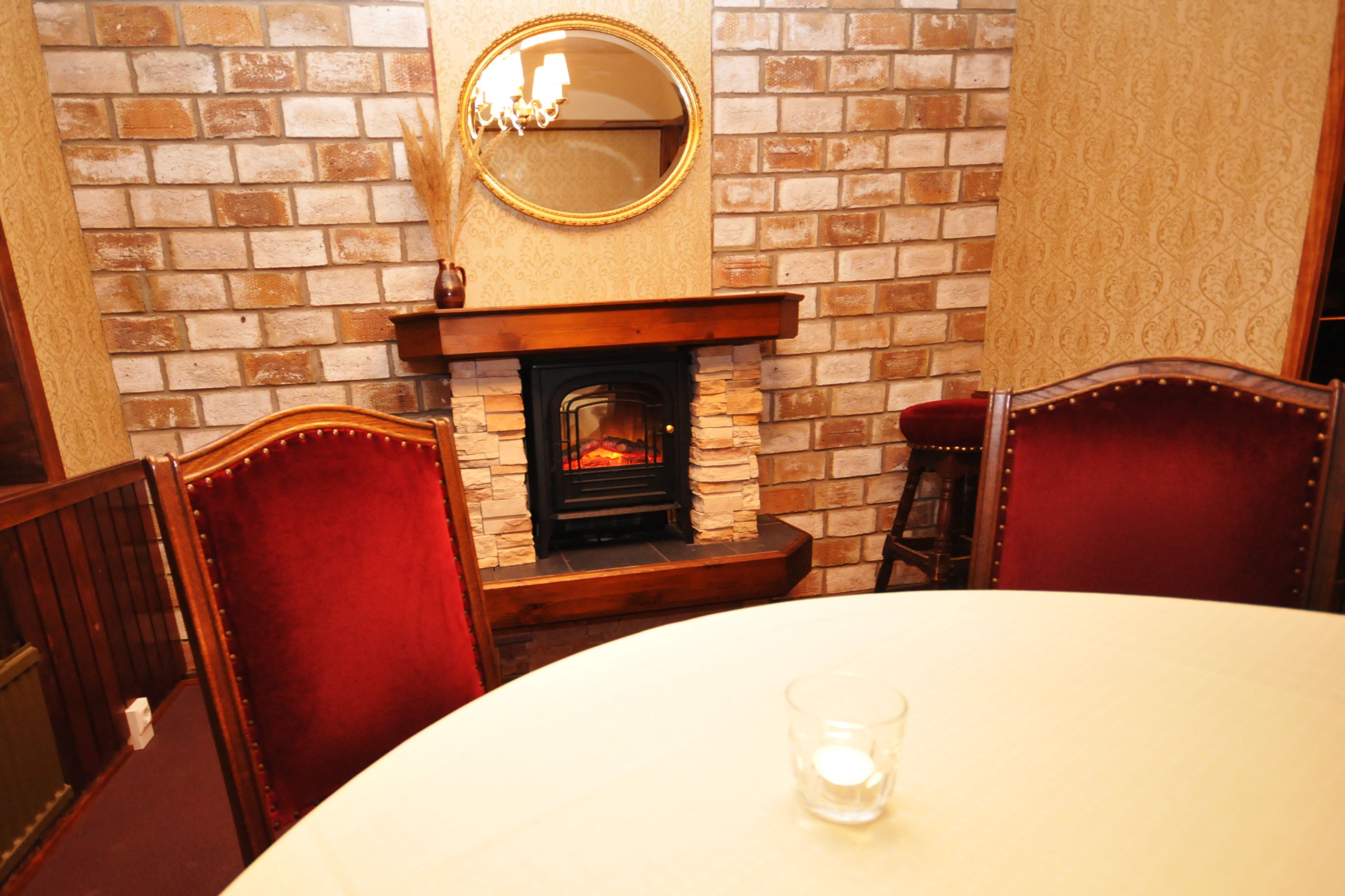 Un comedor con chimenea de ladrillo, sillas de madera y una mesa redonda.