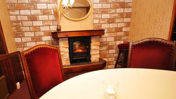 Un comedor con chimenea de ladrillo, sillas de madera y una mesa redonda.