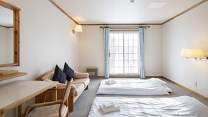 A hotel room with a desk, two beds, a chair, a window with curtains, and a lamp. - The Heritage (Kutchan)