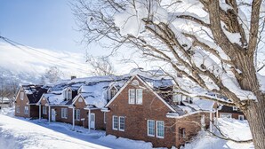 A brick house with multiple chimneys and snow-covered roofs. - The Heritage (Kutchan)