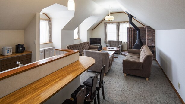 A spacious loft with a kitchen area, seating, and a fireplace. - The Heritage (Kutchan)
