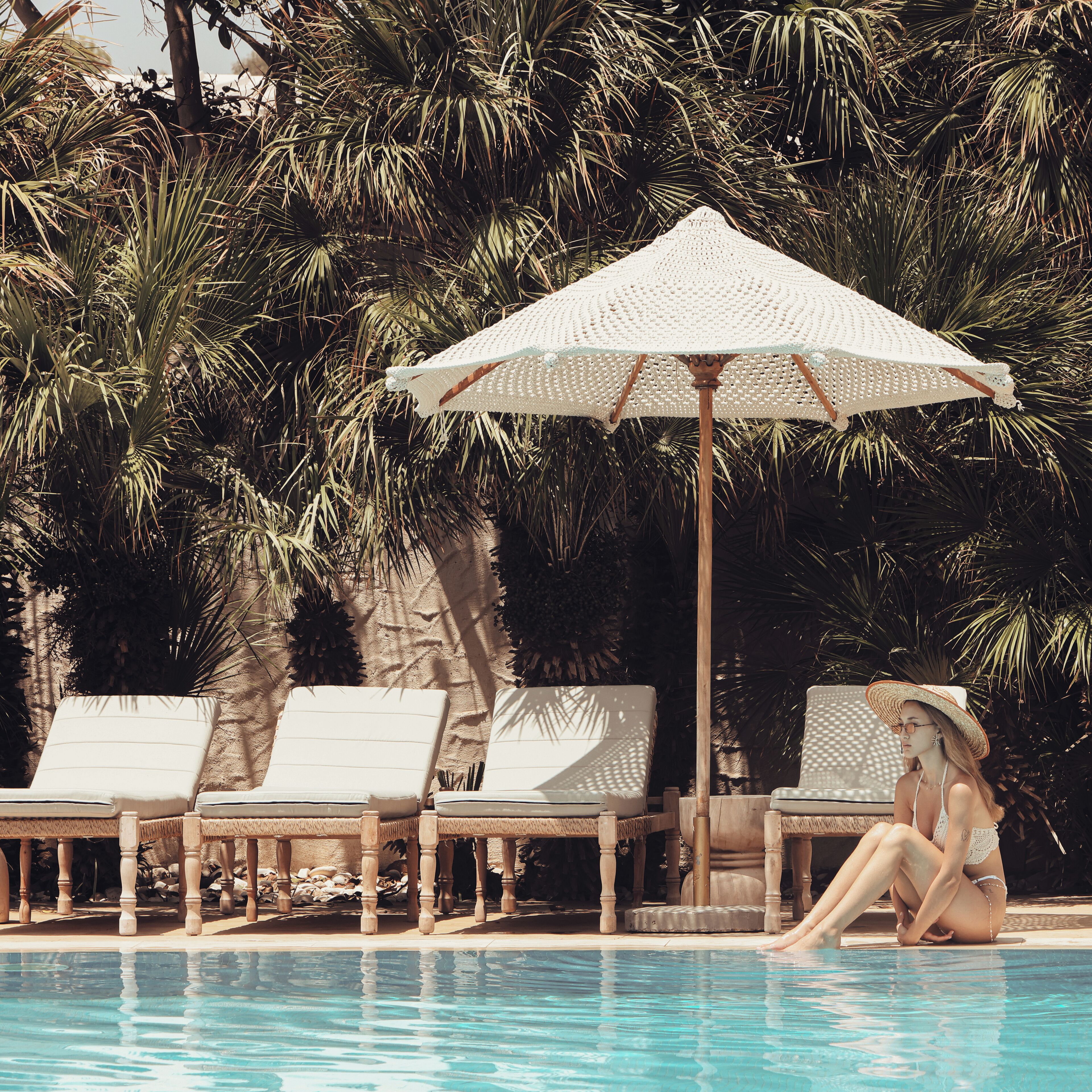 A poolside area with lounge chairs and a large umbrella.