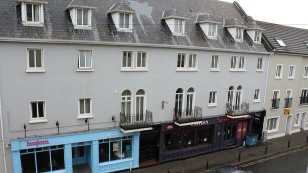 Un immeuble à plusieurs étages, doté de différentes boutiques, dont une façade bleue sur laquelle on peut lire l’inscription « boojurn ».