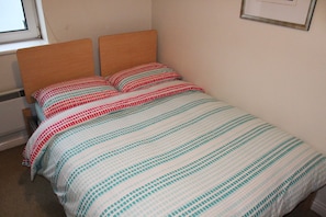 Un lit simple avec une tête de lit en bois et une couvre-lit à rayures.