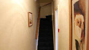 Un couloir étroit avec un escalier menant à une porte.