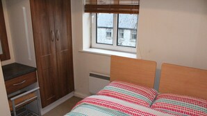 Une chambre à coucher avec un lit, une armoire, un radiateur et une fenêtre.