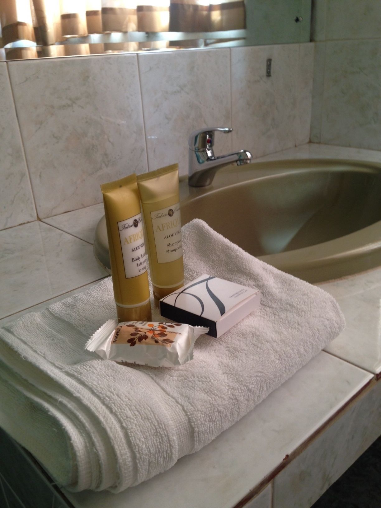 A bathroom with a bathtub, a towel, and toiletries including body lotion and shampoo.