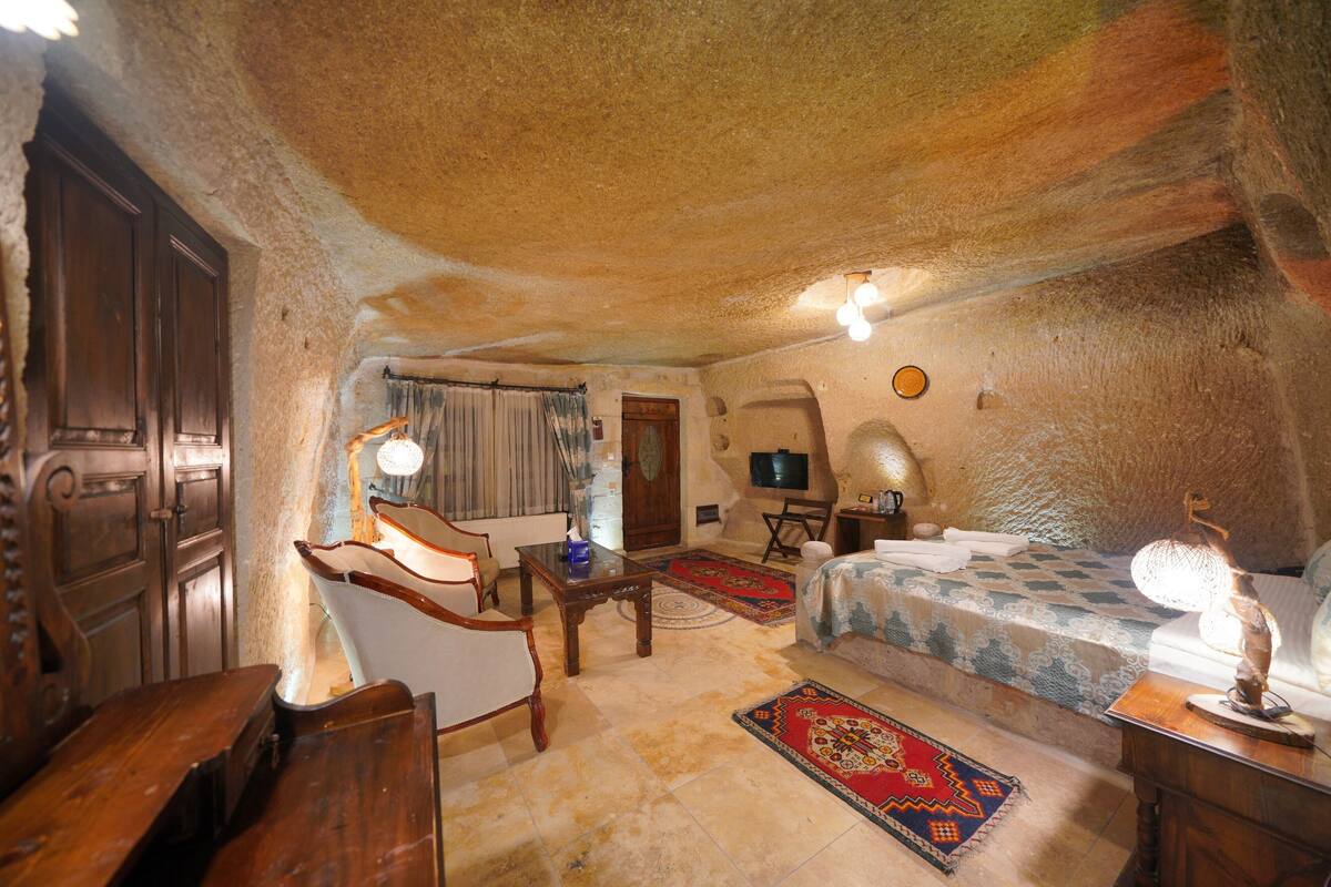 A cozy, rustic room with a bed, wooden furniture, a television, and a decorative lamp.