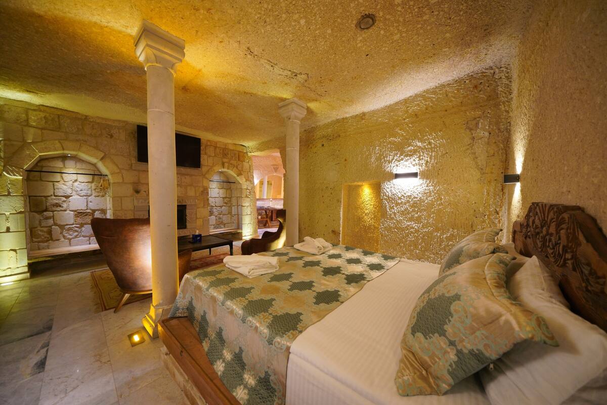 A room with a bed, a chair, and a stone wall.
