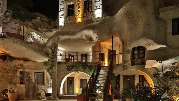 Un edificio de piedra con un exterior rústico, semejante a una cueva, que cuenta con una escalera y arcos.