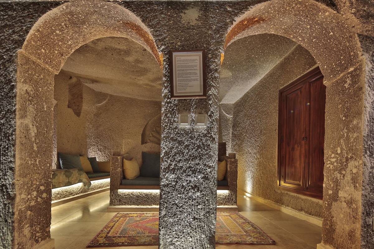 A stone-walled hallway with a wooden door and a framed plaque on the wall.