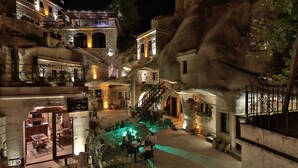 Un hotel con un patio que cuenta con piscina, arquitectura de piedra y zonas de estar al aire libre.