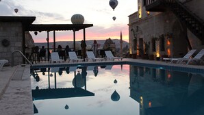 Zona de piscina con sillas de descanso y vista al atardecer.