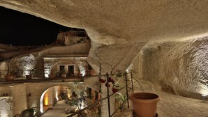 Un interior con paredes de piedra, una escalera y plantas en macetas.