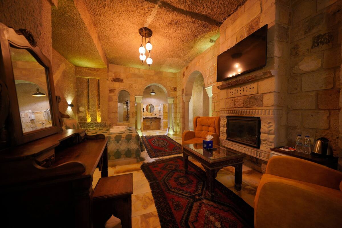 A cozy room with a fireplace, stone walls, and a television mounted on the wall.