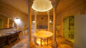 Un área de spa con un jacuzzi, bancos de madera y suelo de piedra.