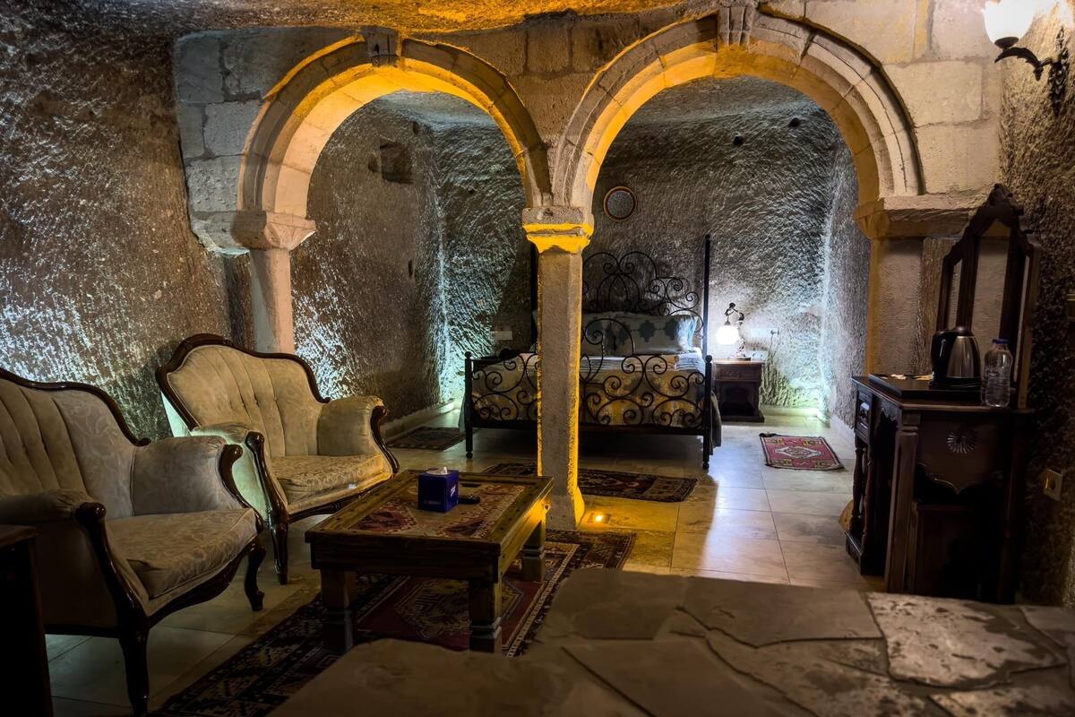 A room with a stone wall, a sofa, a bed, and a table.