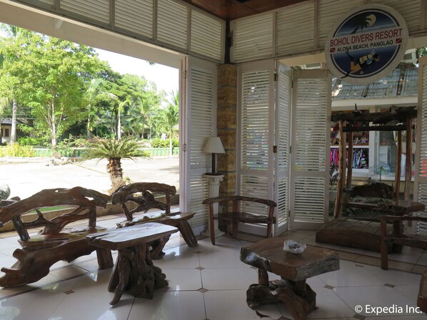 Interior de madera con una mesa, sillas y un cartel de Bohol Divers Resort, con vistas al exterior.