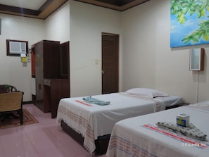 A hotel room with two beds, a wooden wardrobe, a small desk, and a painting on the wall. - Bohol Divers Resort (Tagbilaran)