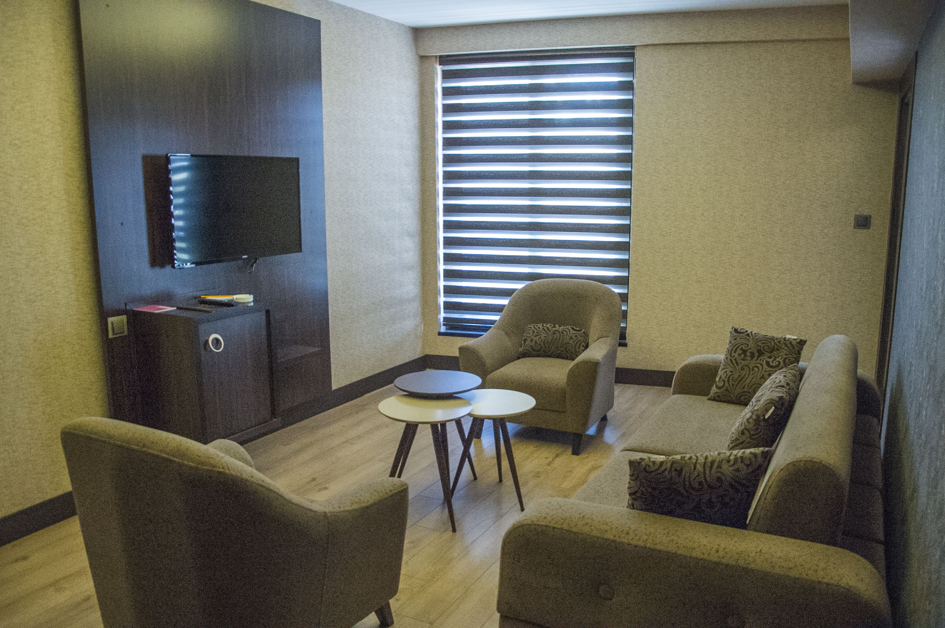 Una sala de estar moderna con un televisor de pantalla plana, un sofá, sillones y una mesita de centro.