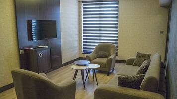 Una sala de estar moderna con un televisor de pantalla plana, un sofá, sillones y una mesita de centro.