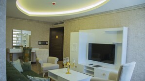 Una sala de estar moderna con un televisor de pantalla plana, una mesa de centro blanca y un sofá verde.