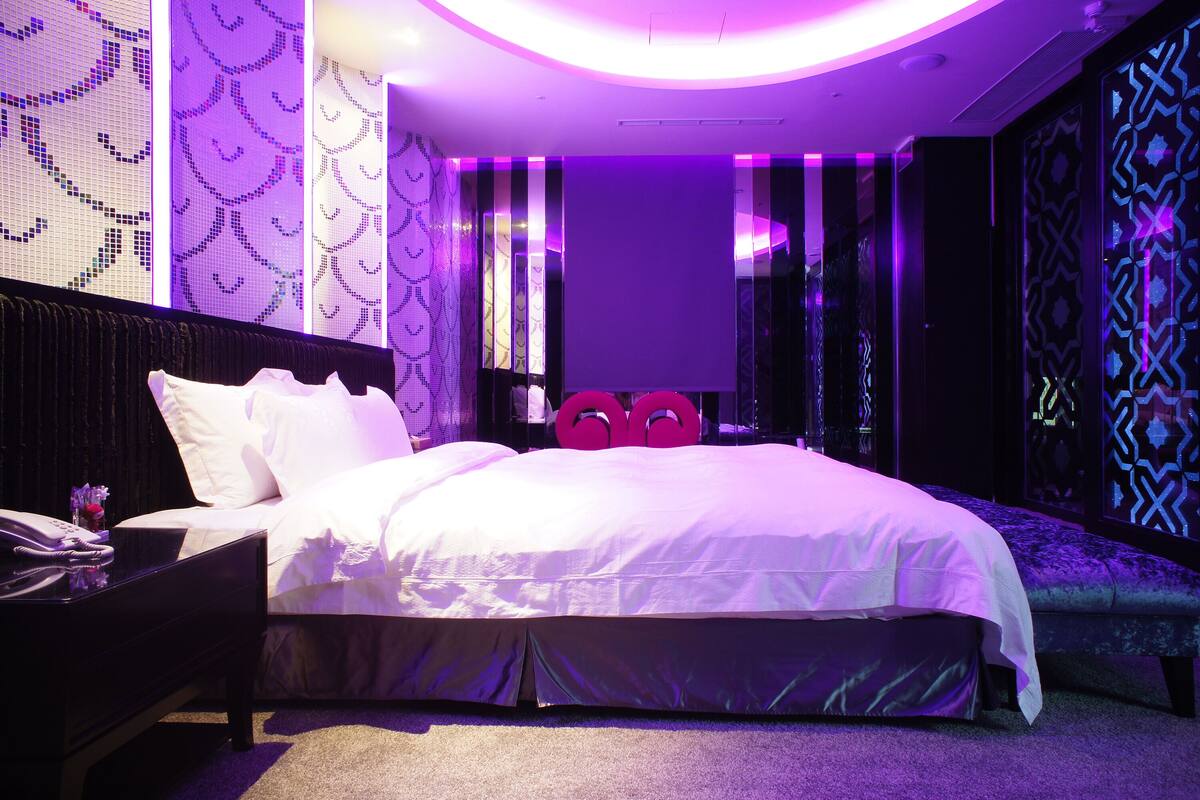Habitació d'hotel moderna amb un llit gran, una taula de nit i un mirall.