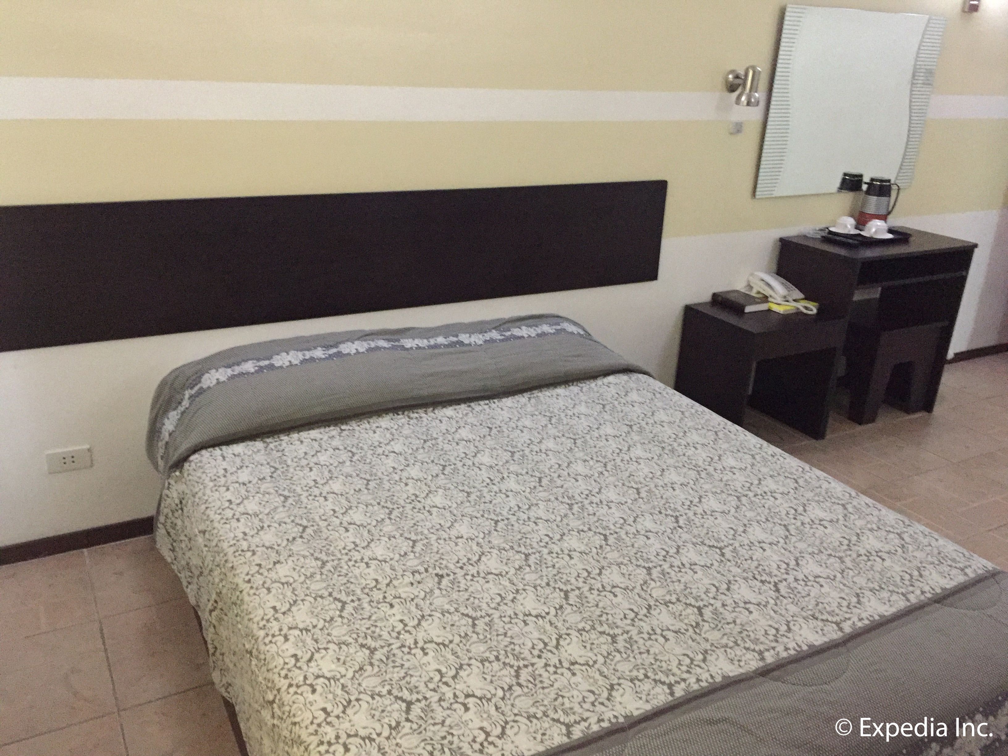 A hotel room with a bed, a desk, a chair, a telephone, and a mirror.