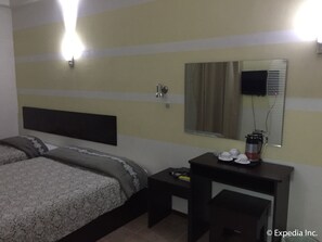 A hotel room with a bed, bedside table, and a desk with a mirror. - Metro Park Hotel Mandaue (Mandaue)