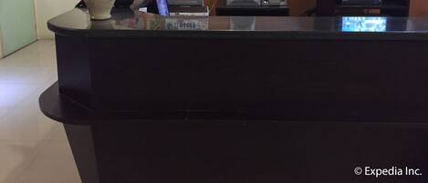 A reception desk with a flower arrangement, a city license plate, a speaker, and a television.