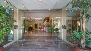 A hotel lobby with glass doors, potted plants, and a marble floor. - Astir Beach (Zakynthos)
