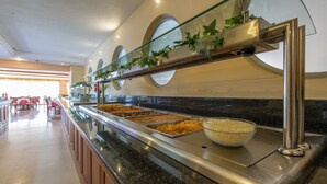 A buffet area with multiple food stations and a glass railing. - Astir Beach (Zakynthos)