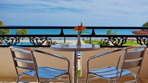 A balcony with a table and two chairs, overlooking a body of water. - Astir Beach (Zakynthos)