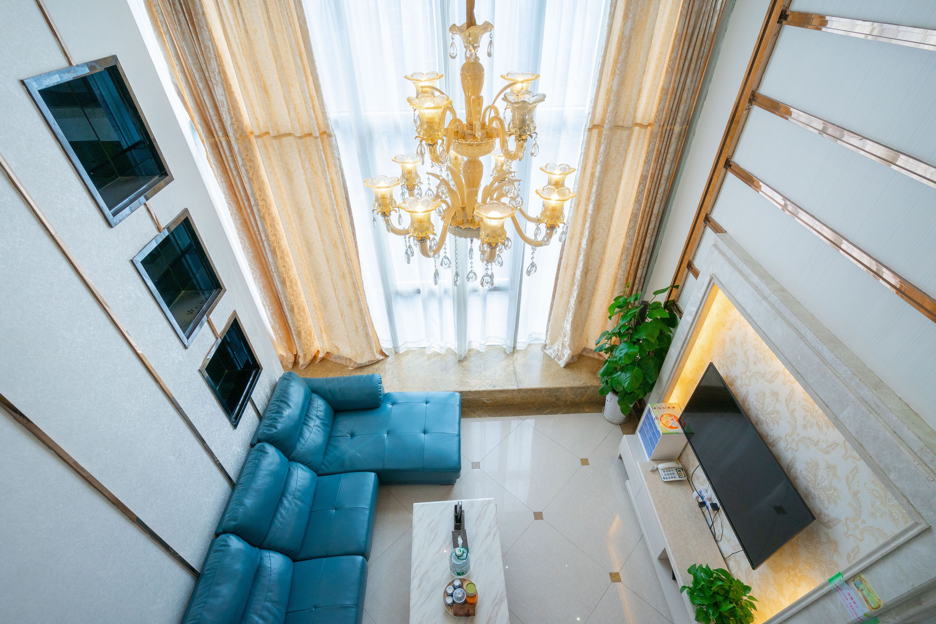 A modern living room with a blue sofa, a chandelier, and a fireplace.
