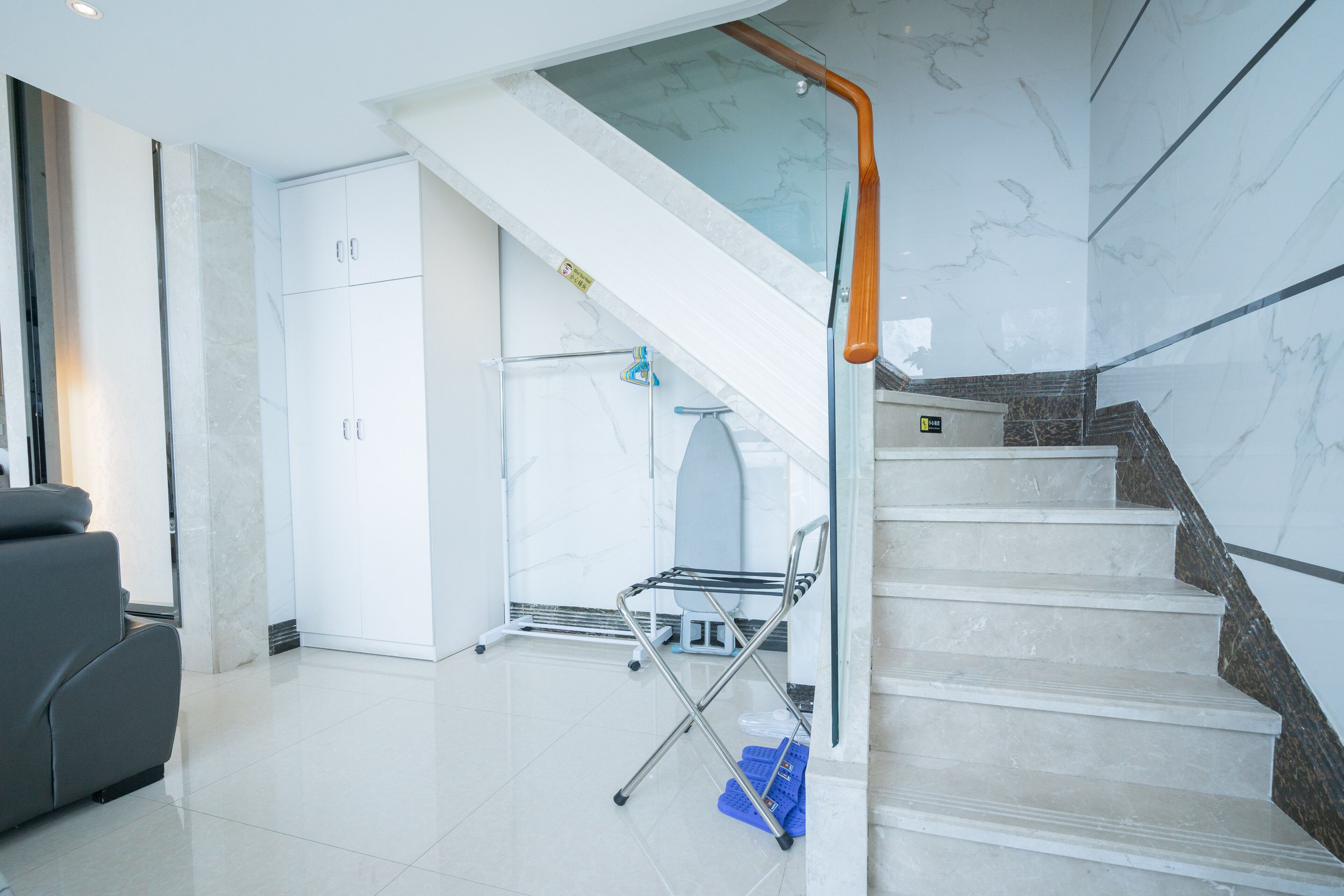 A modern hotel lobby with a marble staircase, a seating area, and a glass railing.
