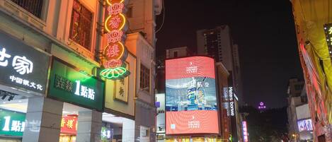 A busy urban street at night with illuminated signs and billboards, including a prominent Turkish Airlines advertisement.